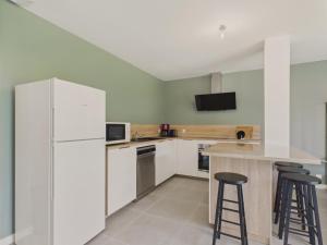 eine Küche mit einem weißen Kühlschrank und zwei Barhockern in der Unterkunft Jardin clos - Maison de plain-pied pour 4 in Le Tour-du-Parc + 10 Fotos