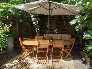 a wooden table and chairs under an umbrella at Le Nid Bord De La Loire in Orléans