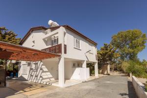 une maison blanche avec un escalier sur le côté dans l'établissement Laranca Oneiro Seaside Villa, à Perivólia