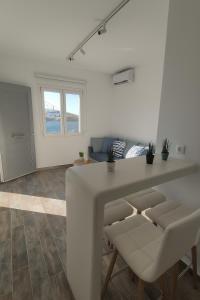 Una sala de estar blanca con una mesa y sillas. en Alos Seafront Gem - Loutra Seaview Escape, en Loutra