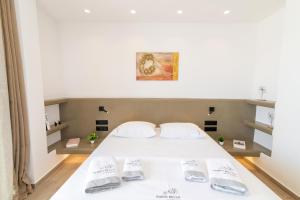 a bedroom with a white bed with two slippers at Porto Bello Tinos in Agios Ioannis