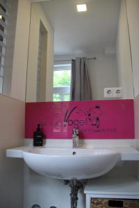 a bathroom sink with a pink sign on the wall at Apartment Charmant in Jena