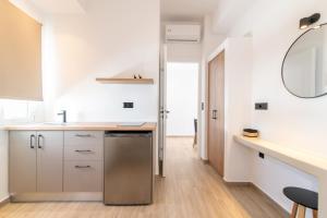 a kitchen with white cabinets and a sink and a mirror at Porto Bello Tinos in Agios Ioannis