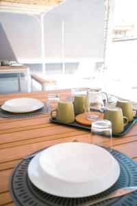 a wooden table with white plates and glasses on it at Dal Monaco - casa blu in Castellana Grotte