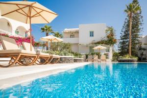 a swimming pool with chairs and umbrellas next to a building at Joanna Villas in Kamari