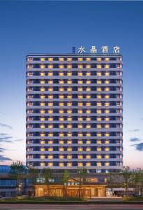 un grand bâtiment avec une enseigne sur le côté dans l'établissement Crystal Hotel Qingdao The Mall of Splendors, à Qingdao