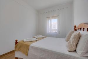 una camera da letto bianca con un letto con due asciugamani sopra di Casa das Orquídeas ad Aljezur