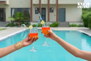 two people holding cocktails in front of a pool at StayVista at Eleganza Villas & Resort, Jaipur in Jaipur