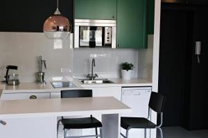 cocina con armarios verdes y encimera blanca en Emerald Mokotowska 59, en Varsovia