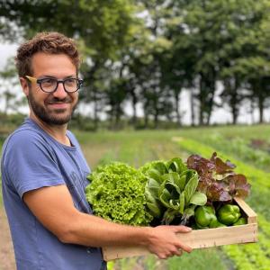 a man holding a wooden box filled with vegetables at Parcel Tiny House Ty Pois 1, près de la pointe de la torche in Plonéour-Lanvern +14 photos