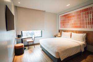 清迈ibis Chiang Mai Nimman Journeyhub的一间卧室，配有一张床、一张书桌和一扇窗户