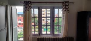 a window with curtains and a view of a building at Amu Ghumounte Stay in Pātan