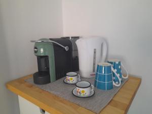 a coffee maker and three cups on a wooden shelf at Una sosta a Buti in Buti