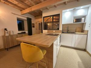 a kitchen with a wooden table and yellow chairs at Gîte de charme en Ardèche in Saint-Étienne-de-Fontbellon