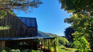 a wooden cabin in the middle of a field with trees at Okuti Retreat in Little River