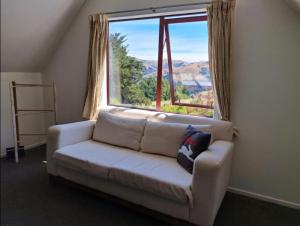 a couch in a room with a large window at Okuti Retreat in Little River +5 photos
