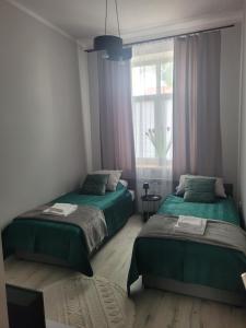 a bedroom with two beds and a window at Apartamenty MILANHOUSE in Gołdap +2 photos