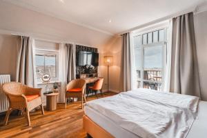 a bedroom with a bed and a table and chairs at Hotel Hüttmann in Norddorf