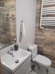 a white bathroom with a toilet and a sink at Apartamenty MILANHOUSE in Gołdap