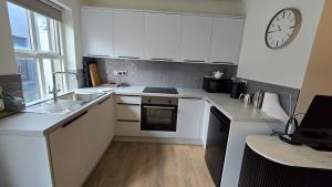 a kitchen with white cabinets and a clock on the wall at Galway City Centre, 3 bedroom, sleeps 6 in Galway