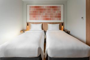 清迈ibis Chiang Mai Nimman Journeyhub的两张白色的床,彼此相邻,位于一个房间里