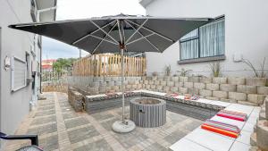 a patio with an umbrella and a bench and a grill at Villa Dubaai in Mossel Bay