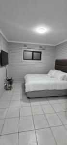 Un dormitorio blanco con una cama y un televisor. en Grace Villas 35, en East London
