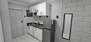 a kitchen with a refrigerator and a white brick wall at Grace Villas 35 in East London