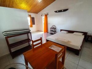 a bedroom with a bed and a wooden table at Hôtel-bungalows La Pirogue in Sambava