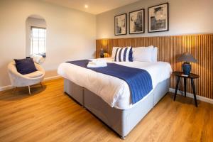 a bedroom with a large bed and a chair at The Coach House Suffolk in Lowestoft