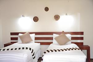 two beds in a room with white and brown stripes at Chobe Sunset Chalets in Lesoma