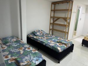 a room with two beds and a book shelf at Habitación cerca a la playa 104 in Cartagena de Indias