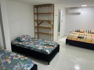 a room with two beds and a book shelf at Habitación cerca a la playa 104 in Cartagena de Indias