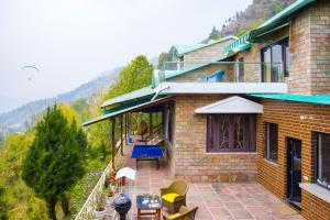 ein Haus mit einer Terrasse mit Tisch und Stühlen in der Unterkunft Heaven on Hills by The StayCationer in Bhīm Tāl