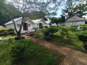 a white house with a tree in the yard at Hôtel-bungalows La Pirogue in Sambava