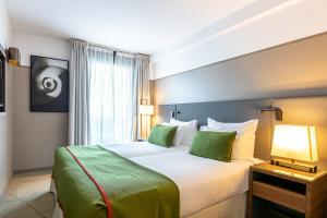 Cette chambre comprend un grand lit avec des oreillers verts. dans l'établissement Fraser Suites Paris La Défense, à Courbevoie 37 autres photos