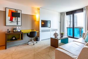 un salon avec un canapé et un bureau dans l'établissement Fraser Suites Paris La Défense, à Courbevoie