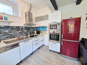 a kitchen with white cabinets and a red refrigerator at Duplex Apartment Valter Strunjan in Strunjan