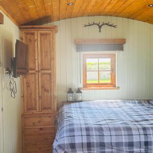 a bedroom with a bed and a window at Stratford Bespoke Shepherd Hut in Snitterfield