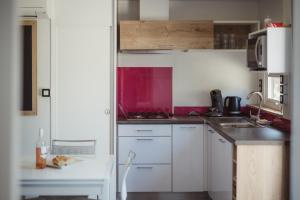 Una pequeña cocina con gabinetes blancos y un fregadero. en Domaine Les Mûriers, en Vendres-Plage 47 fotos más