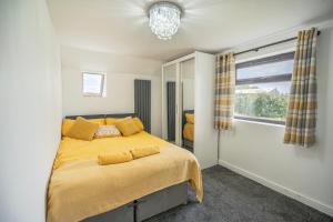 a bedroom with a bed with yellow sheets and a window at Spacious Countryside Barn House in Little Bridgeford