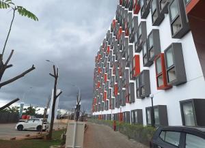 a white building with red windows on a street at Apartemen Bandaraya Tallasa City in Makassar