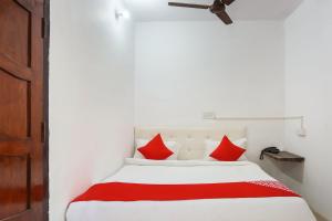 a bedroom with a white bed with red pillows at Hotel O Gold Stayz in Ballabgarh