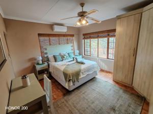 een slaapkamer met een bed en een plafondventilator bij Lion's Pride - Marloth Park in Marloth Park