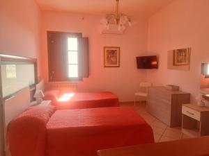 a bedroom with two red beds and a window at La rosa del castello in Castrovillari