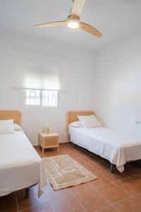 a bedroom with two beds and a ceiling fan at Los jardines de Zahora C02 in Cádiz