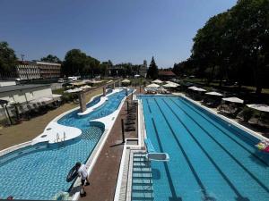 a large swimming pool with people standing around it at Holiday Beach Budapest Wellness Hotel with Sauna Park in Budapest