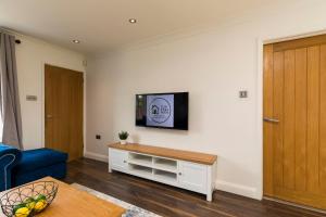 a living room with a blue couch and a tv on a wall at Hazel House Spacious 3BR Home Parking WiFi Contractor Friendly in Ifield