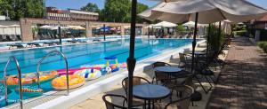a swimming pool with tables and umbrellas and chairs next to a swimming pool at Holiday Beach Budapest Wellness Hotel with Sauna Park in Budapest