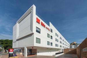 清迈ibis Chiang Mai Nimman Journeyhub的白色的建筑,上面有红色的标志